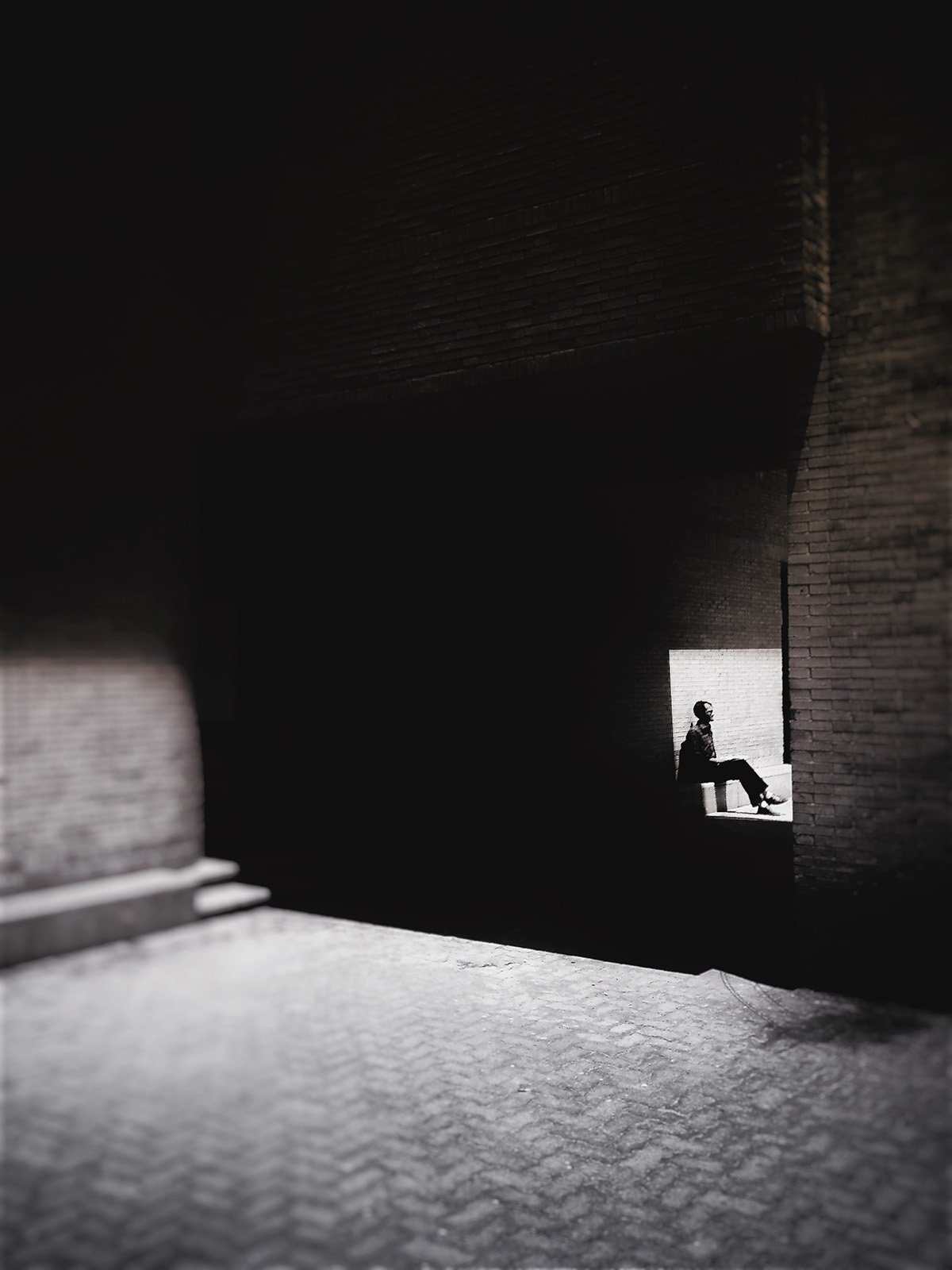 Minimalist street photography from the 'Urban Eclipse' series, featuring silhouettes and sharp geometric shadows against urban brick architecture.