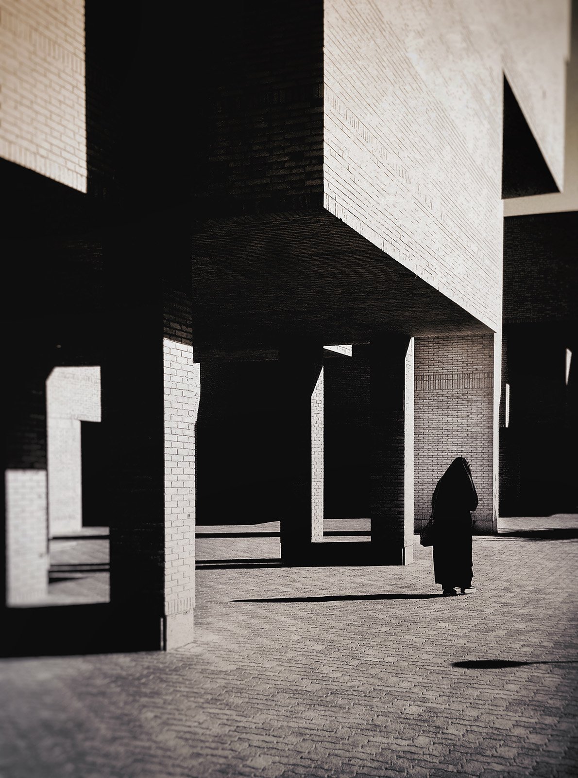 Minimalist street photography from the 'Urban Eclipse' series, featuring silhouettes and sharp geometric shadows against urban brick architecture.