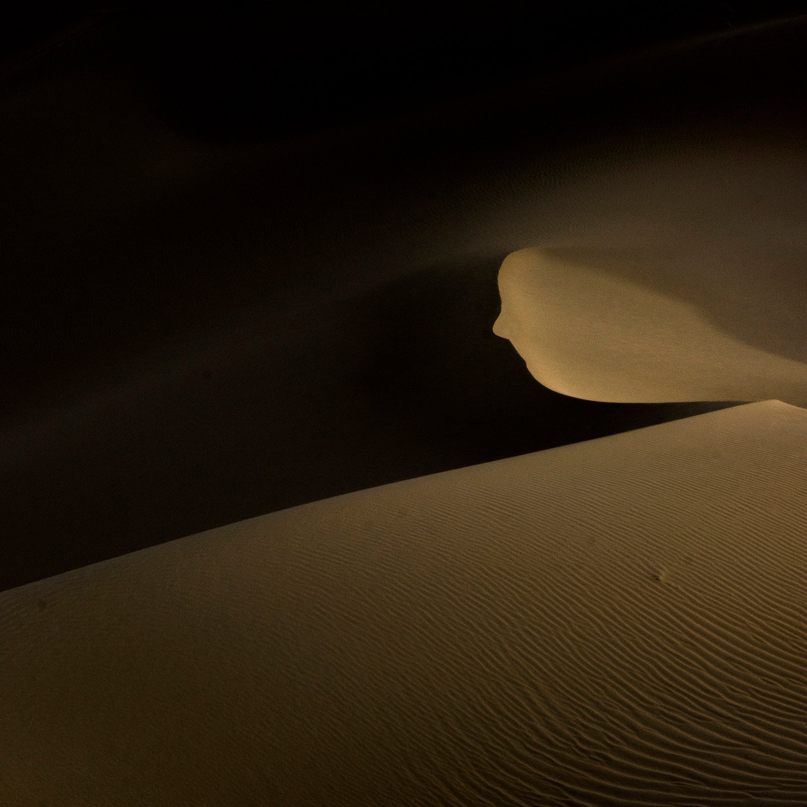 Minimalist photograph of desert sand dunes with soft light, abstract curves, and subtle textures creating a quiet atmospheric composition.