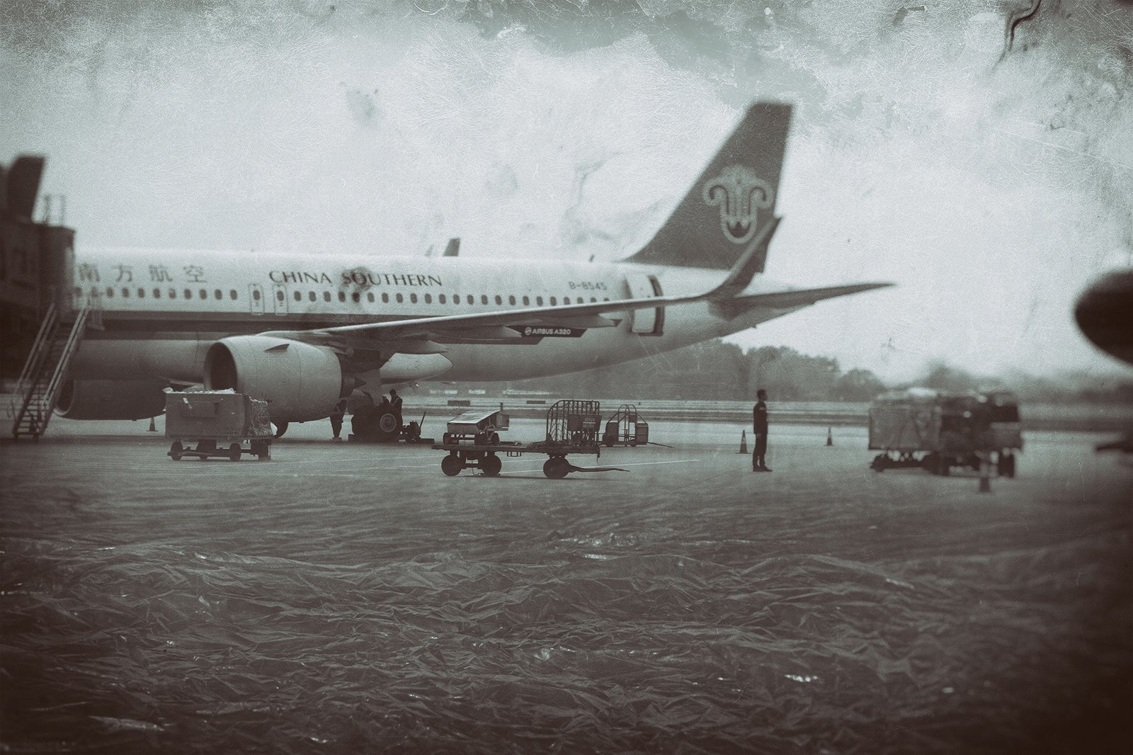A China Southern airplane at an airport with the ground covered in a sea of plastic waste, from the 'This Will Destroy Us' photography series.